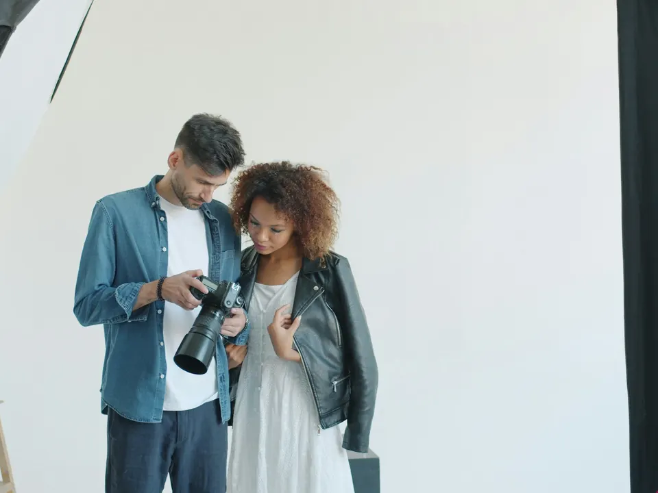 A photographer and model reviewing shots on a camera in a studio